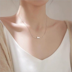 Détail du collier argenté minimaliste avec pendentif chat sur barre incurvée sur mannequin