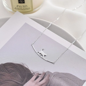 Détail d'un pendentif chat minimaliste en argent sur une fine chaîne de collier délicate