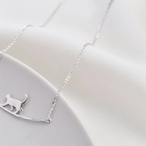 Collier chat minimaliste en argent avec un pendentif chat marchant sur une barre courbée