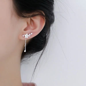 Macro detail of S925 silver flower earrings with pink zircon accents and hanging tassels
