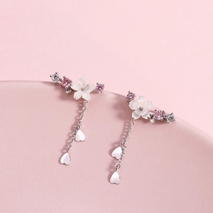 Detail of silver cherry blossom earrings with white shells, pink zircons and heart drops