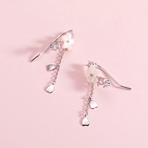 Detail of silver floral drop earrings with white petals and heart-shaped metal pendants