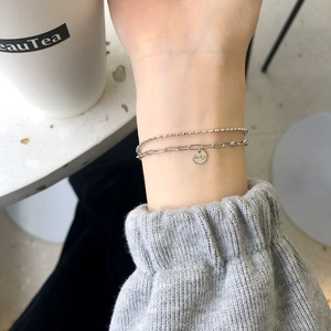 Macro detail of S925 sterling silver double-layer bracelet with lucky engraved round tag