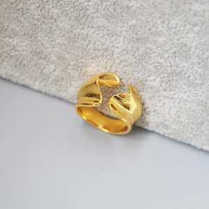 Minimalist irregular wavy open gold ring with polished finish on grey velvet