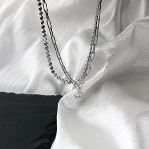 Detailed macro view of silver double-layered necklace with lucky engraved round pendant