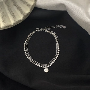 Detail of S925 sterling silver double layer bracelet with lucky round tag on black fabric