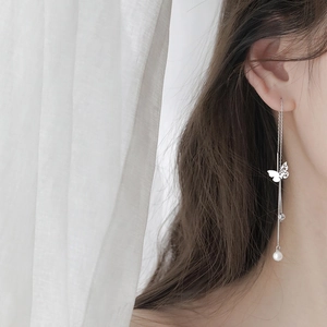 Detail of silver butterfly tassel earrings with pearl drop on a model profile