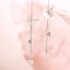 Detailed close-up of butterfly tassel earrings with silver chains and white pearls