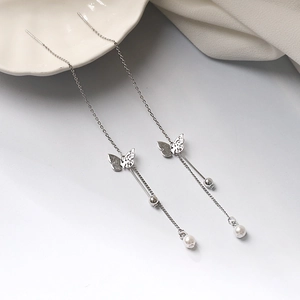 Macro view of butterfly tassel earrings with silver finish and white pearl drops