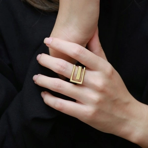Detailed view of wide geometric gold ring with rectangular frame and vertical bar