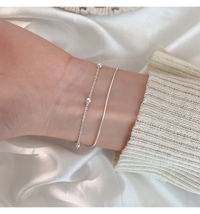 Detail of silver double-layered bracelet with beads and snake chain on wrist