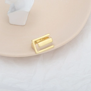Detailed view of wide hollow rectangular gold ring on an elegant ceramic plate