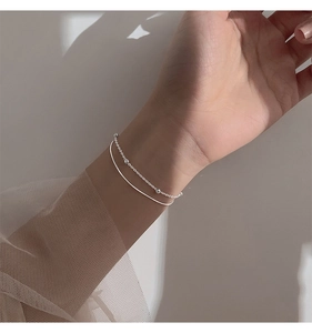 Close-up of minimalist double-layer silver bracelet with small beads on a female wrist