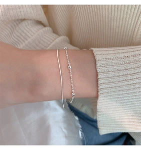 Close-up of double-layered silver snake and bead chain bracelet on a female wrist