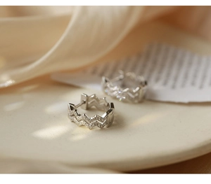 Macro shot of silver wavy ear cuffs with micro-paved cubic zirconia on silk fabric