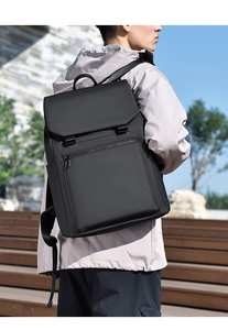 Outdoor side view of a matte black waterproof backpack showing the sleek ergonomic straps