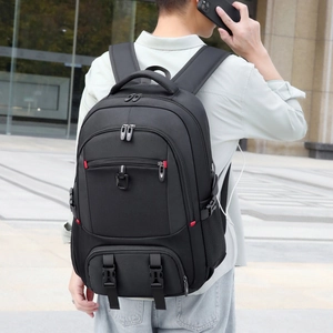 Detail of black travel backpack showing the USB charging port and red zipper accents