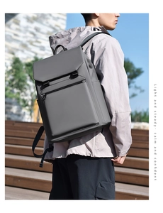 Outdoor shot of a gray waterproof business backpack featuring a large front zipper pocket