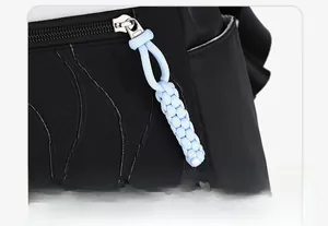 Detail view of wave-quilted black fabric with light blue hand-woven zipper puller