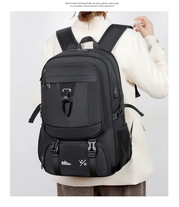 Black travel backpack showing USB charging port, carabiner, and wear-resistant fabric detail