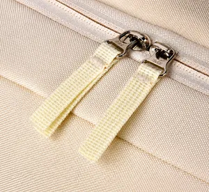 Detail view of smooth dual zippers with long webbing pulls on beige business backpack