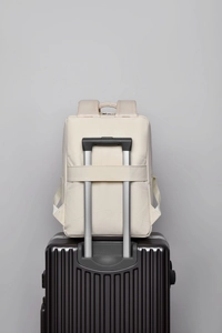 Detail showing back luggage strap of off-white travel backpack on a suitcase handle