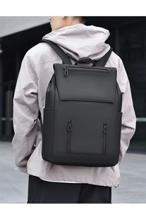 Outdoor shot of a man wearing a large matte black waterproof business travel backpack