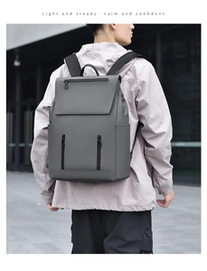 Detailed outdoor view of gray minimalist backpack showing multi-pocket storage and fabric texture