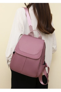 Side view of mauve anti-theft oxford backpack worn by a model in a casual outfit