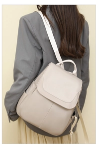 Rear view of a model wearing a beige Oxford fabric anti-theft backpack with flap design