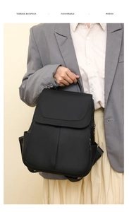 Black nylon anti-theft backpack with flap closure shown held by a fashion model