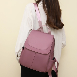 Rear view of model wearing a purple anti-theft oxford backpack with side pockets
