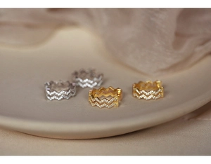 Close-up of gold and silver wavy hoop earrings with micro-pave white zircon on silk