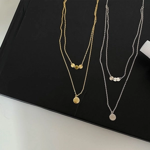 Detail of double-layer sterling silver necklace with Good Luck engraved pendant
