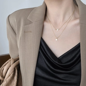 Close-up of double-layered gold necklace with geometric coin pendants on model neck
