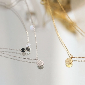 Detail of round coin pendants engraved with Good Luck text on gold and silver necklaces