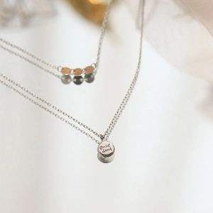 Macro shot of double-layer S925 silver necklace with Good Luck engraved pendant