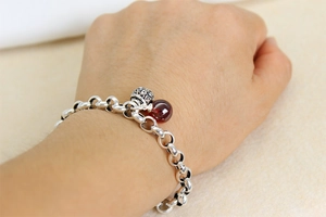 Detail eines Vintage-Thai-Silberarmbands mit roter Achatperle und hohlem Gravuranhänger