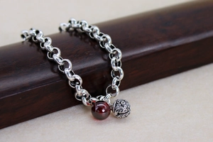 Detail eines Vintage-Silberarmbands mit roter Achatperle und Glocke mit Stern-Mond-Gravur