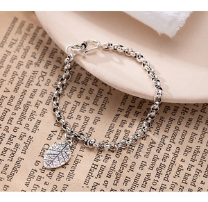 Detailed view of vintage s925 silver leaf pendant on a round link chain bracelet
