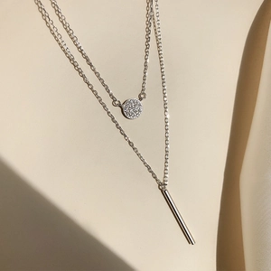 Macro detail of silver double-layered necklace with cubic zirconia disc and bar pendants