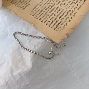 Detail of S925 silver beaded chain bracelet featuring a toggle clasp on vintage paper
