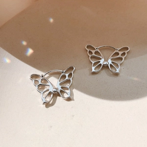 Macro shot of silver hollow butterfly earrings with dreamy rainbow light leaks