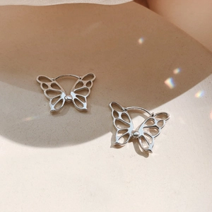 Japanese style hollow butterfly stud earrings in silver finish for women on cream tray