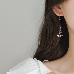 Close-up of silver whale earrings with blue teardrop bead and diamond accents on model