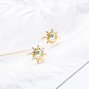 Elegant sunburst stud earrings with blue zircon center displayed on soft white feathers