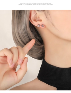 Close-up of S925 silver sunflower earrings with blue zircon on female model's ear