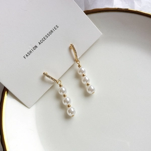 Close-up of elegant long freshwater pearl earrings with zircon inlay in gold finish