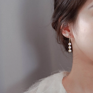 Elegant gold drop earrings with vertical sparkling zircon and three white pearls on model