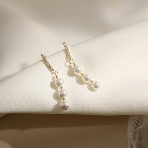 Detail of s925 silver earrings with micro-set zircons and three vertical white pearls
